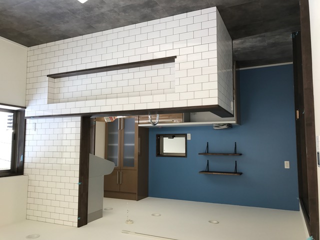 プレーンなホワイトタイルのベージュの目地とバックのブルーの壁