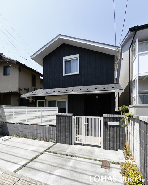 木調のサイディングがグレイッシュな外構と調和する外観の様子